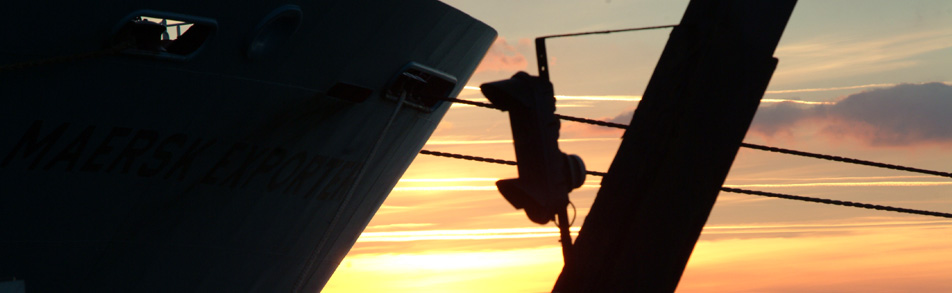 Bows of a cargo ship with the evening sky and mooring lines visible